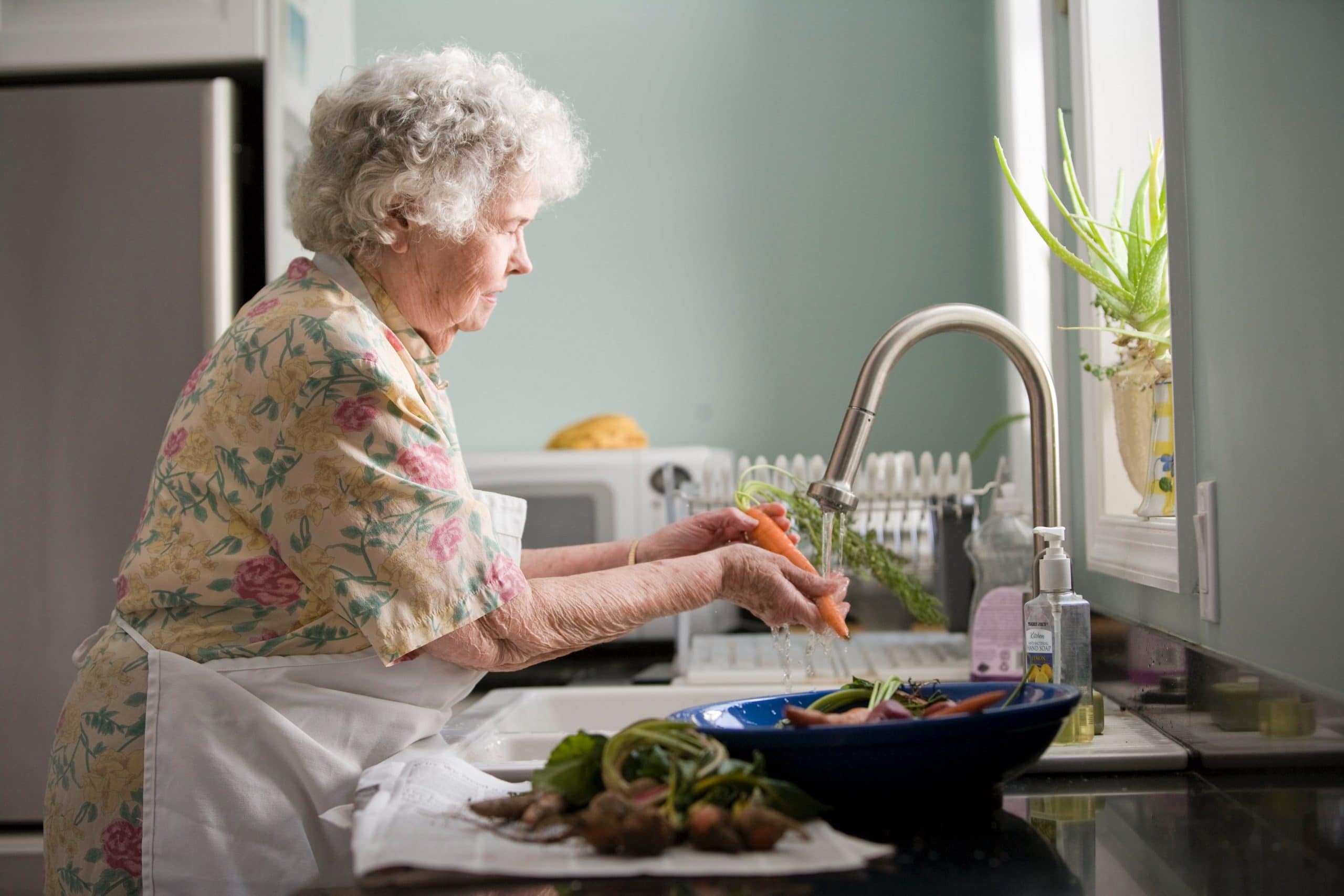 elderly woman washing dishes in kitchen