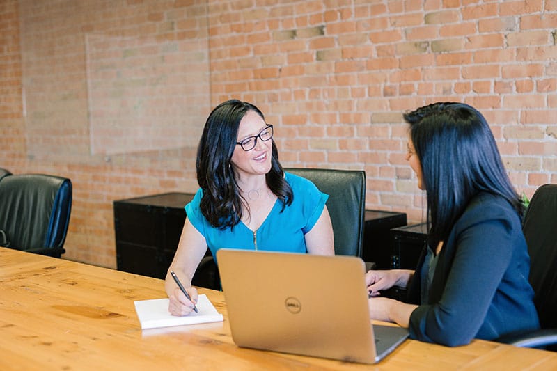 two female business professionals meet in conference room